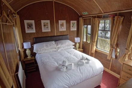 A carefully converted  heritage railway coach in the countryside.